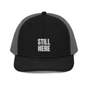 Still Here trucker hat in black and charcoal, front view